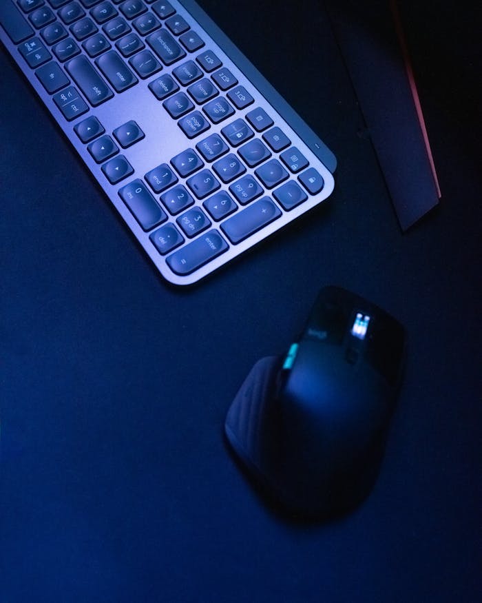 Close-up of a wireless keyboard and mouse on a dark surface, highlighting modern tech design.